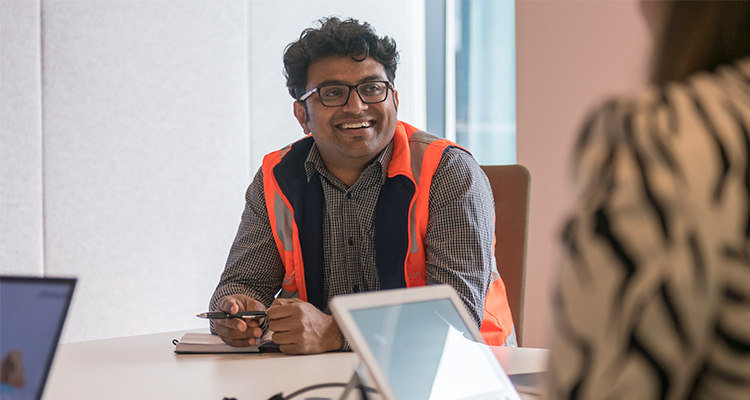 A man sitting at a desk, he is in high-vis clothing.